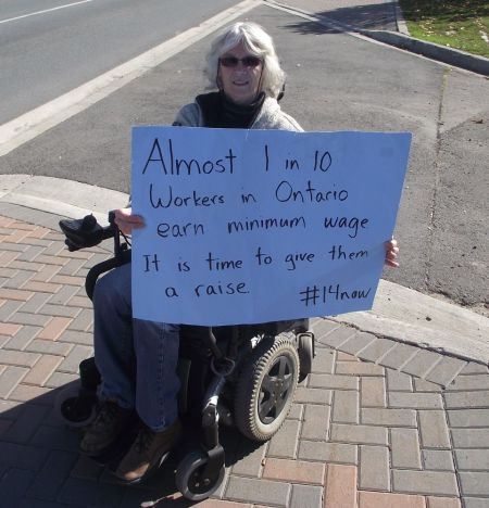 A demonstrator outside Tim Horton's at the corner of Cedar and Paris Streets in Sudbury, Ontario, calling for an increase in the minimum wage to $14 an hour.