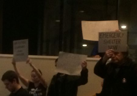 Anti-poverty activists unrolled blankets and sleeping bags on the stairs of the council chambers, and some took out signs indicating their demands. (Photo by Scott Neigh)