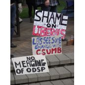 Three signs ready to be taken up for the Friday afternoon march. (Photo by Scott Neigh)