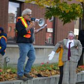 A dummy of Liberal MPP Rick Bartolucci looks on as one of the eleven people arrested last year at his office addresses the crowd. (Photo by Treana Campbell)